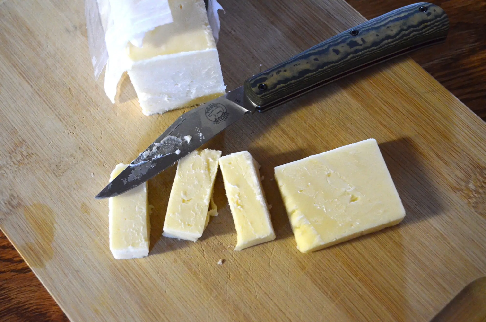 Trailhead Trapper slicing cheese on a cutting board