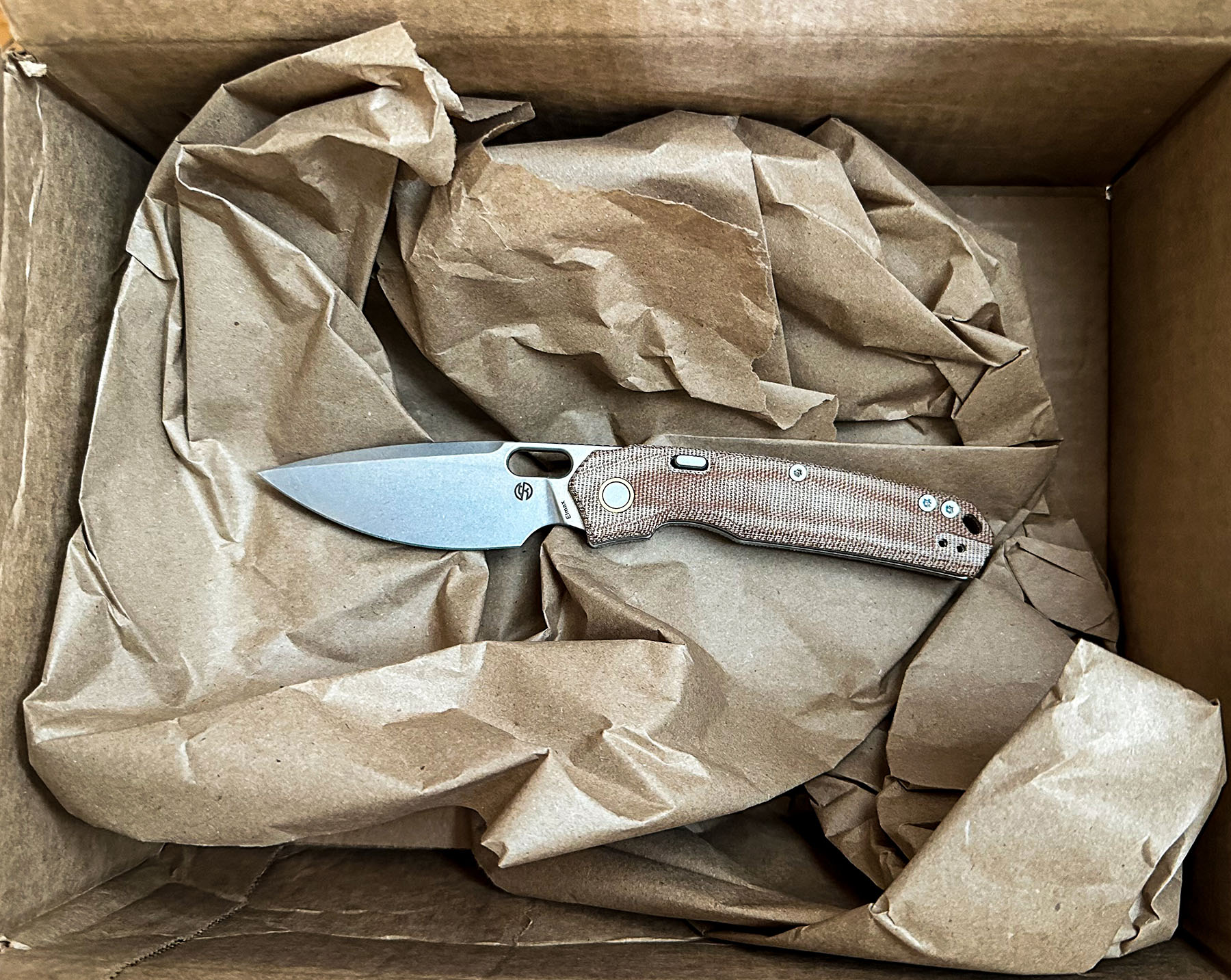 Vosteed Psyop Micarta knife placed inside a cardboard box on brown paper