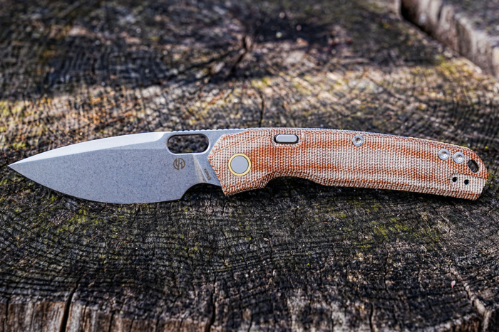 Vosteed Psyop Micarta knife laying flat on a tree stump outdoors