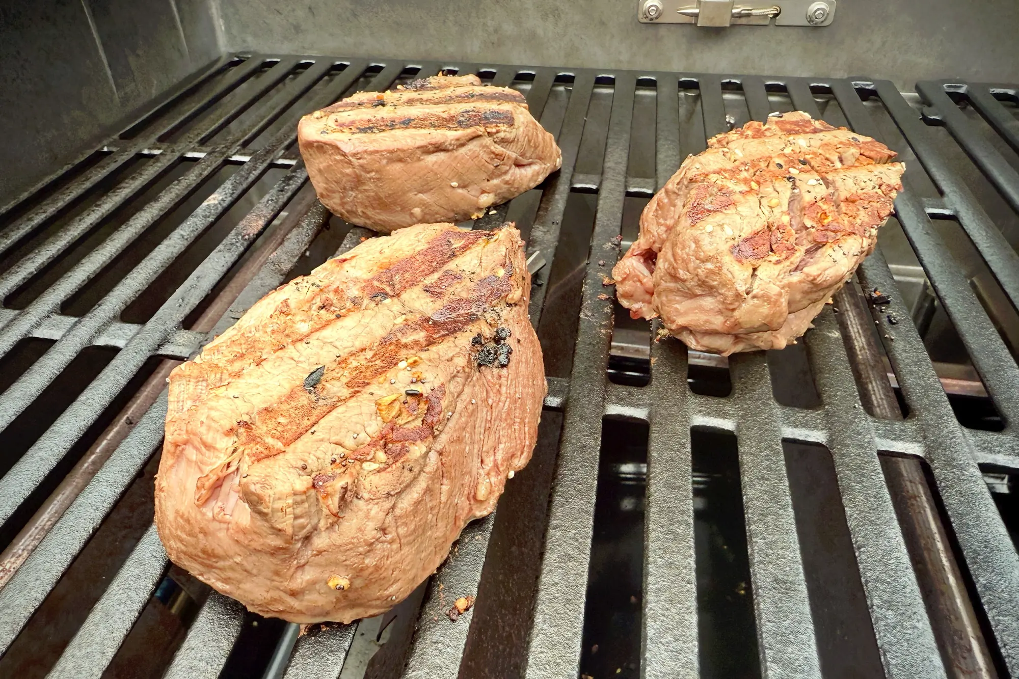 Three grilled steaks with sear marks cooking on the Weber Spirit Propane Grill