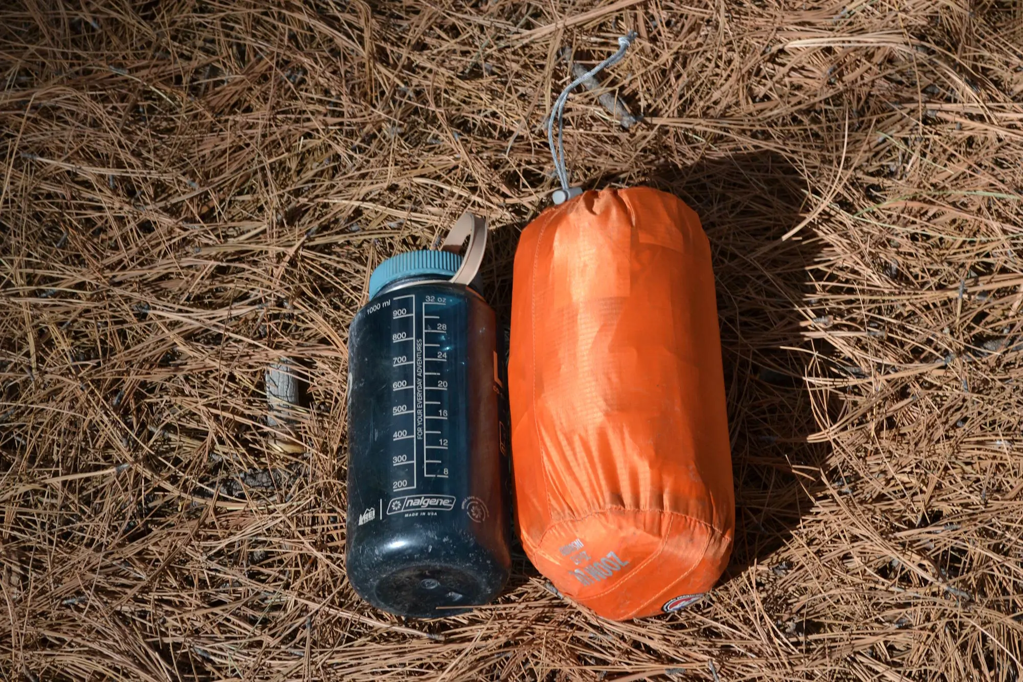 sleeping pad rolled up and stored in its orange stuff sack