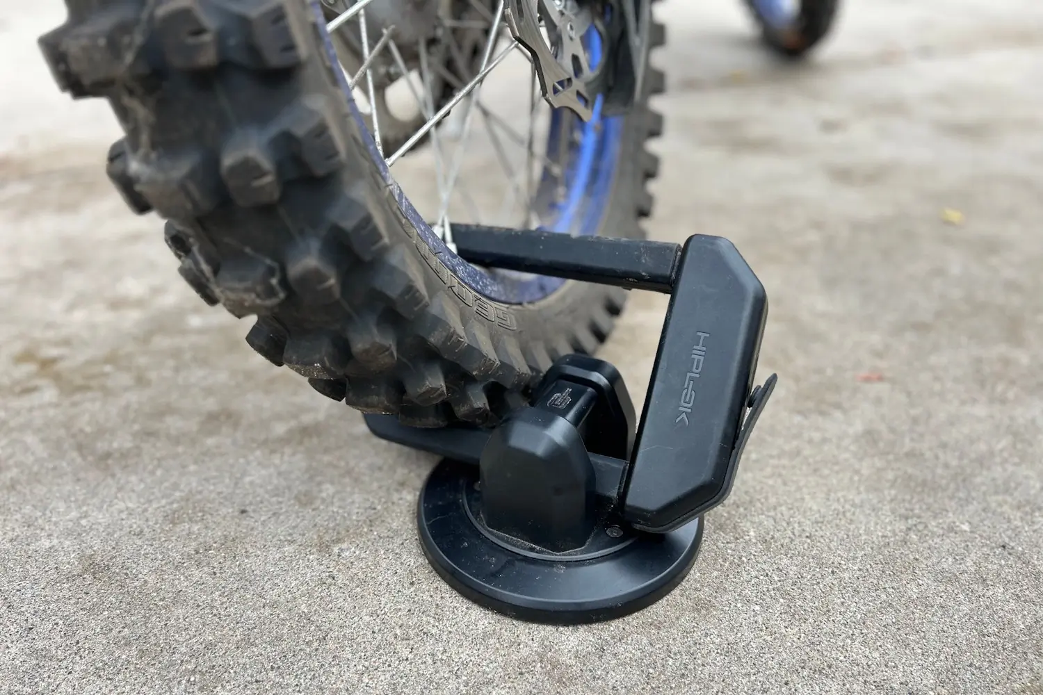 Close-up of a Hiplok DX1000 lock securing a dirt bike wheel on a concrete surface