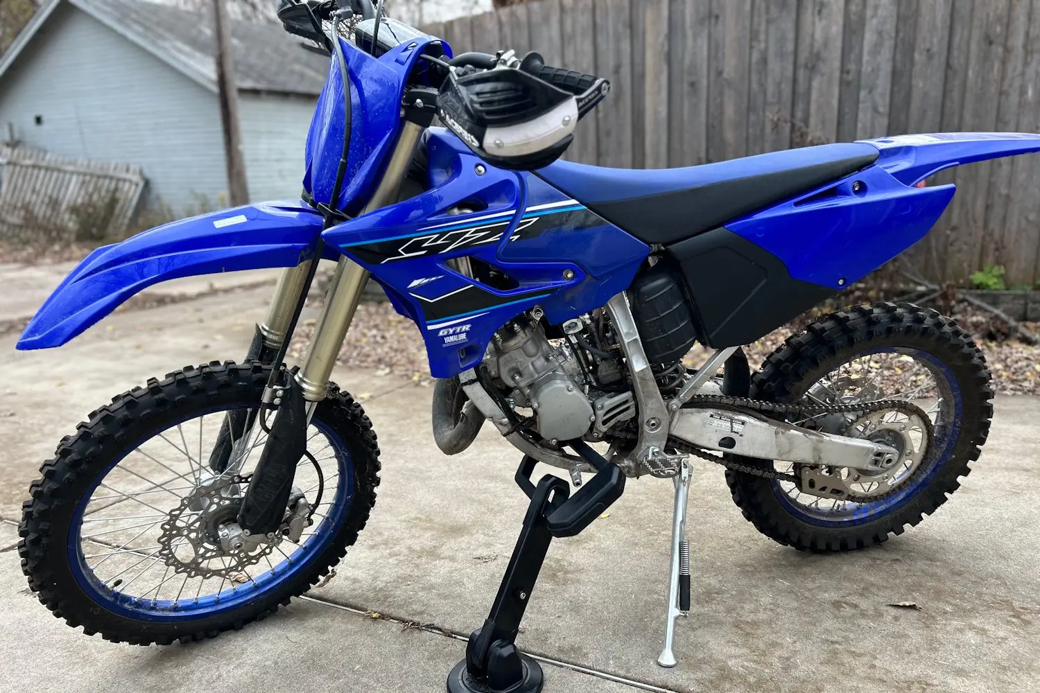 Blue dirt bike secured with the Hiplok DX1000 lock on a concrete driveway