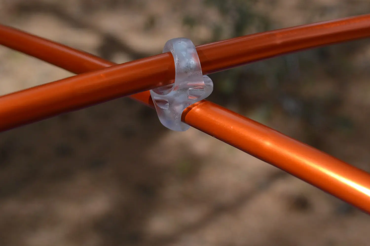Close-up of two intersecting orange tent poles connected by a translucent plastic clip