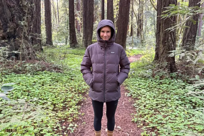 Person wearing a hooded Patagonia puffer jacket on a forest trail