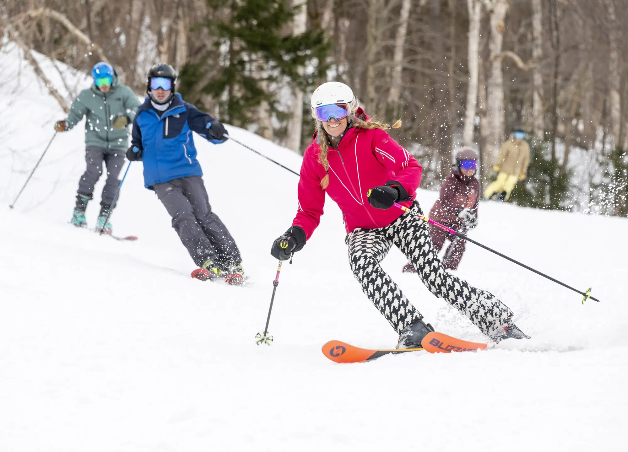 A group skiing down the slope, lead skier wearing Blizzard Black Pearl 88 skis