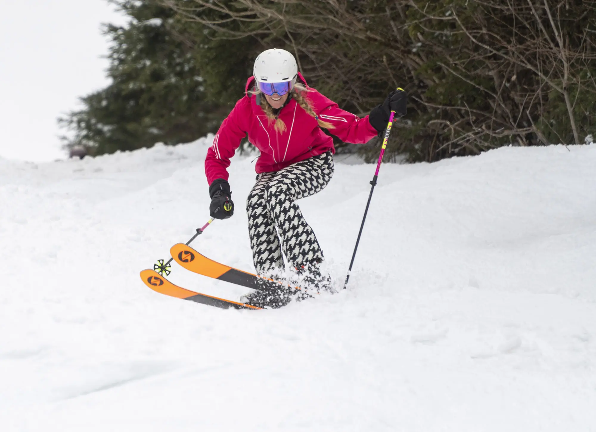 A skier in pink jacket and patterned pants skiing with Blizzard Black Pearl 88 skis
