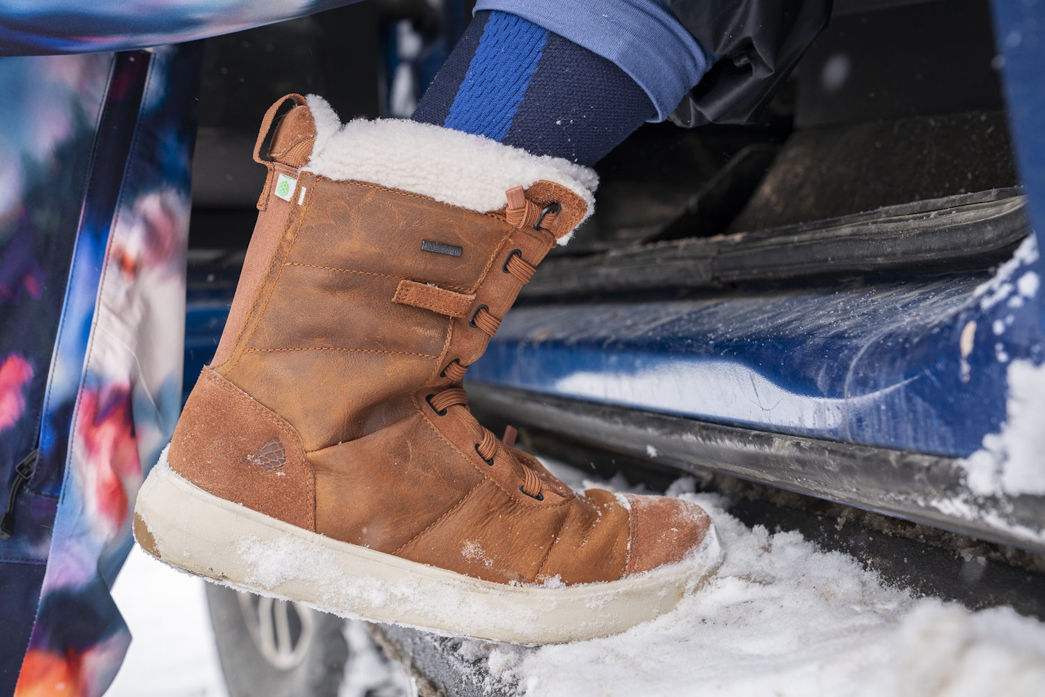 Stio Colter women’s boot stepping onto a snowy vehicle footboard