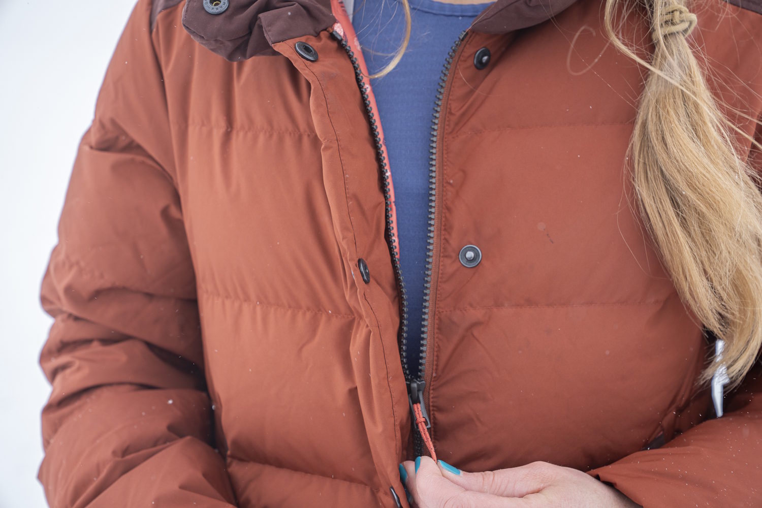 Zipping up the Stio Women's Turnbolt Down Jacket, showing the front zipper and buttons.
