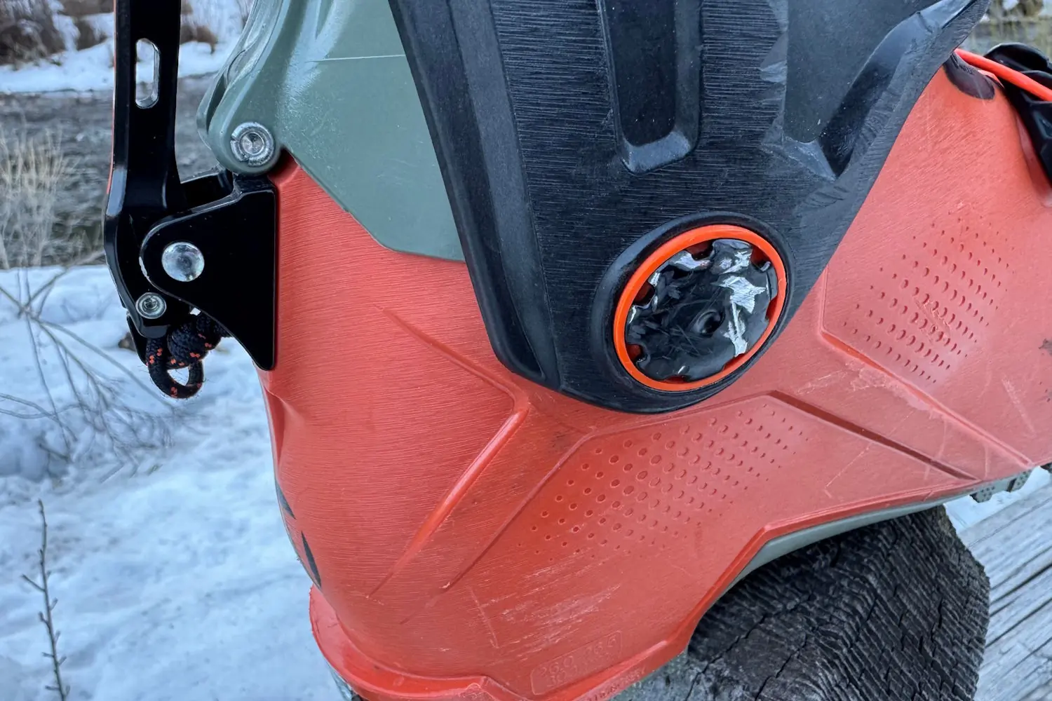 A close-up of a Tecnica ski boot showing a damaged BOA dial and scuff marks on the shell