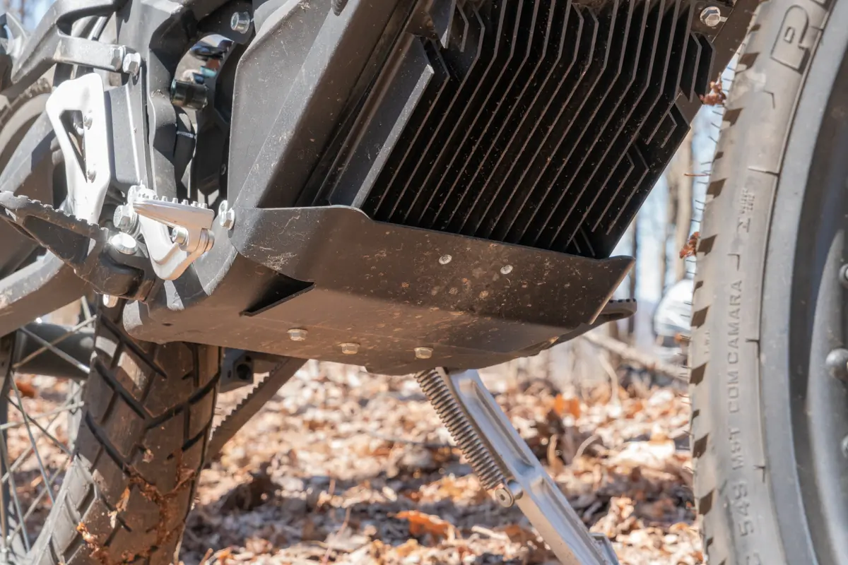 A close-up of the Zero FX electric motorcycle's footpeg and motor mount, with cooling fins visible on the motor housing