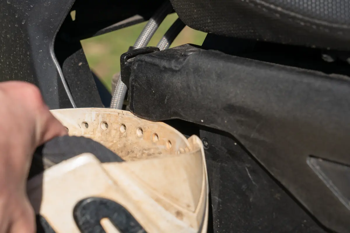 A close-up of a person attaching a helmet to the storage hook on the Zero FX electric motorcycle