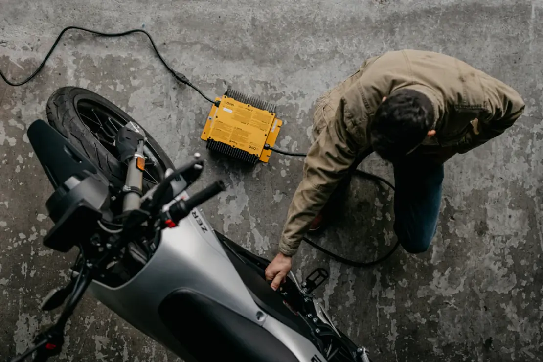 The Zero FX electric motorcycle being charged with the quick charger, set on a concrete surface