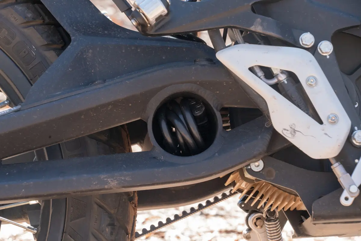 A close-up of the Zero FX electric motorcycle's rear suspension and spring, with the chain and tire visible