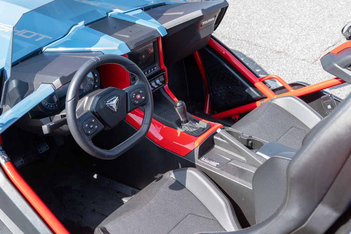 Polaris Slingshot R cockpit view showing the steering wheel, manual gear shifter, and bucket seats