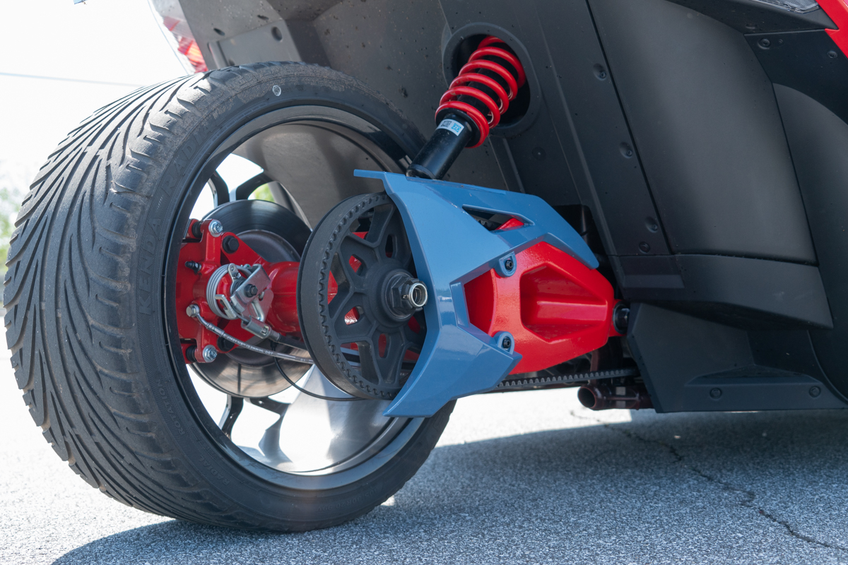 Polaris Slingshot R rear wheel close-up showing belt drive, red hub, and rear suspension