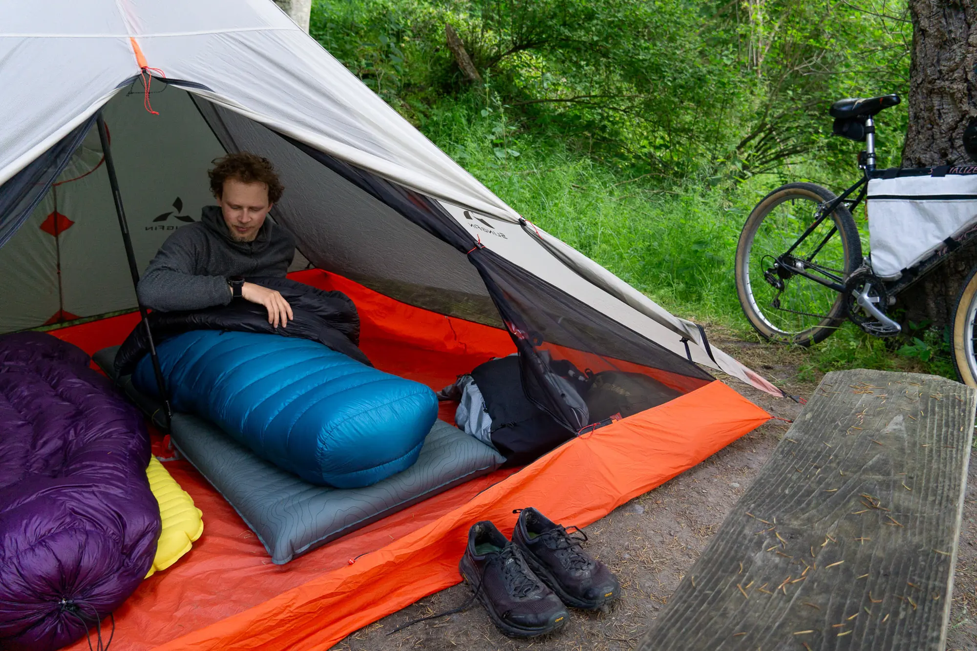 a bikepacker sits up in the katabatic alsek quilt, showing the closed footbox