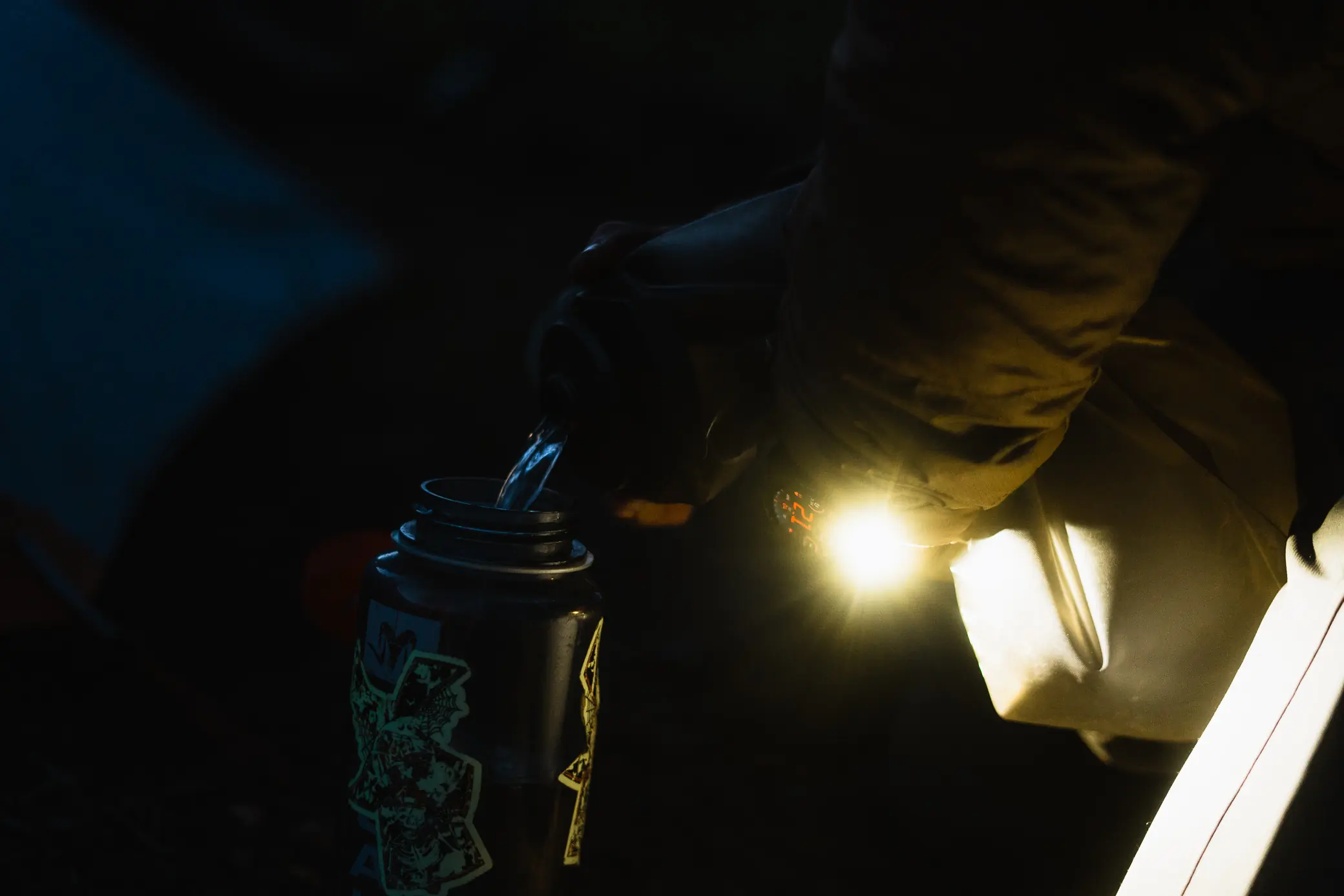 Garmin Tactix 8 Smartwatch flashlight in use while pouring water in the dark