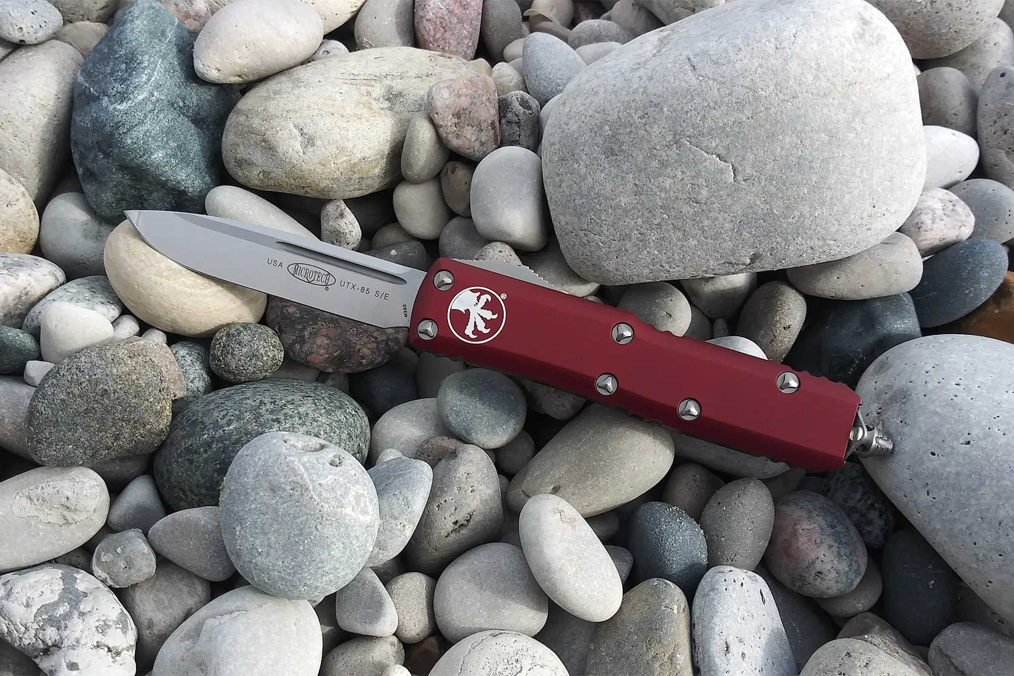 Microtech UTX-85 placed on river stones with blade deployed