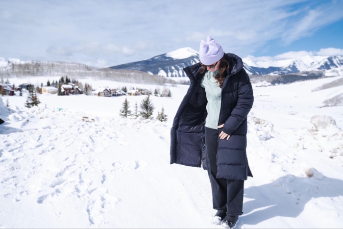 Woman in snow wearing OR Coze Down Parka with open buttons, looking down.