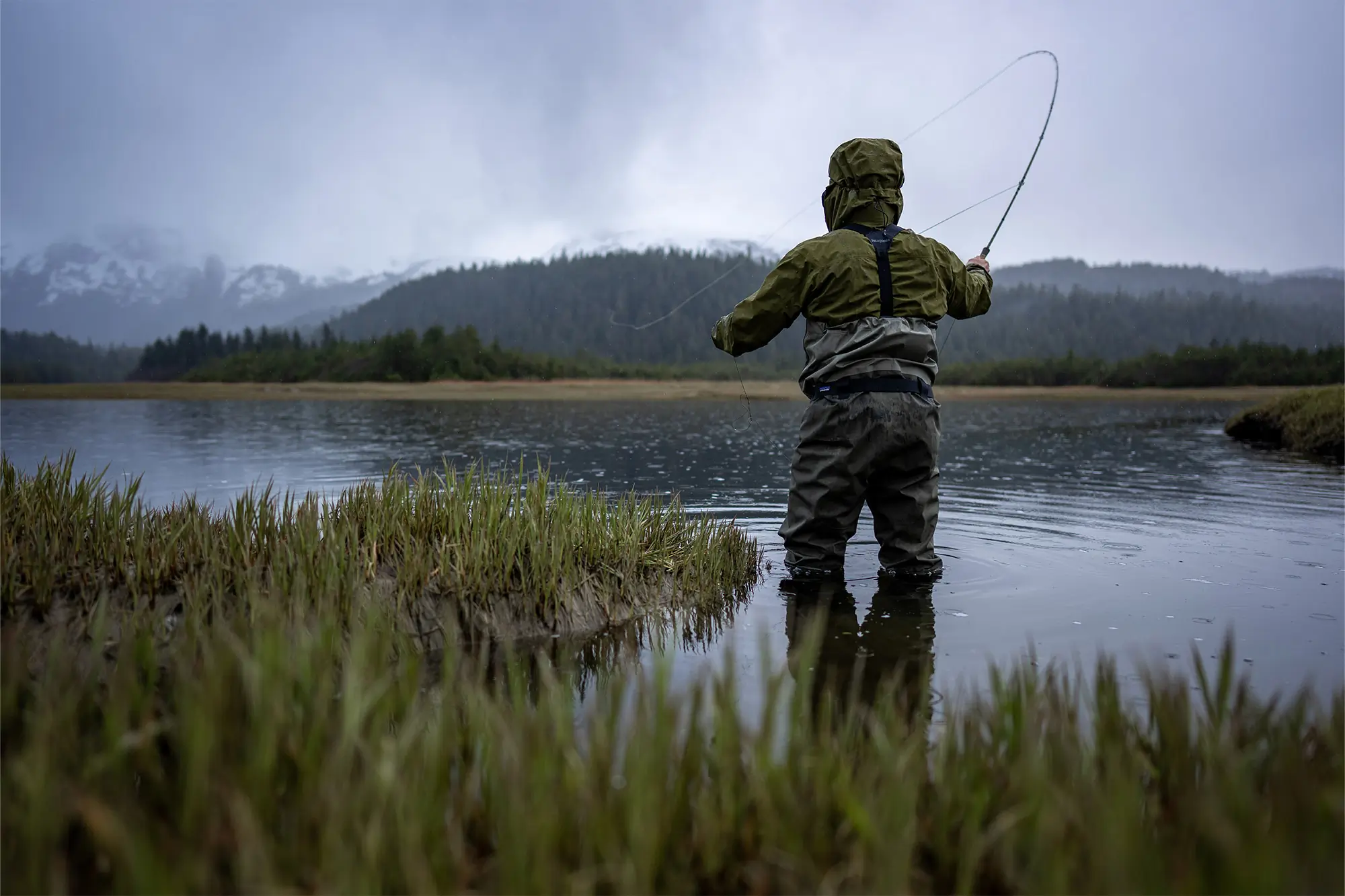 Patagonia Swiftcurrent Traverse Waders in the water from behind while casting a fishing line