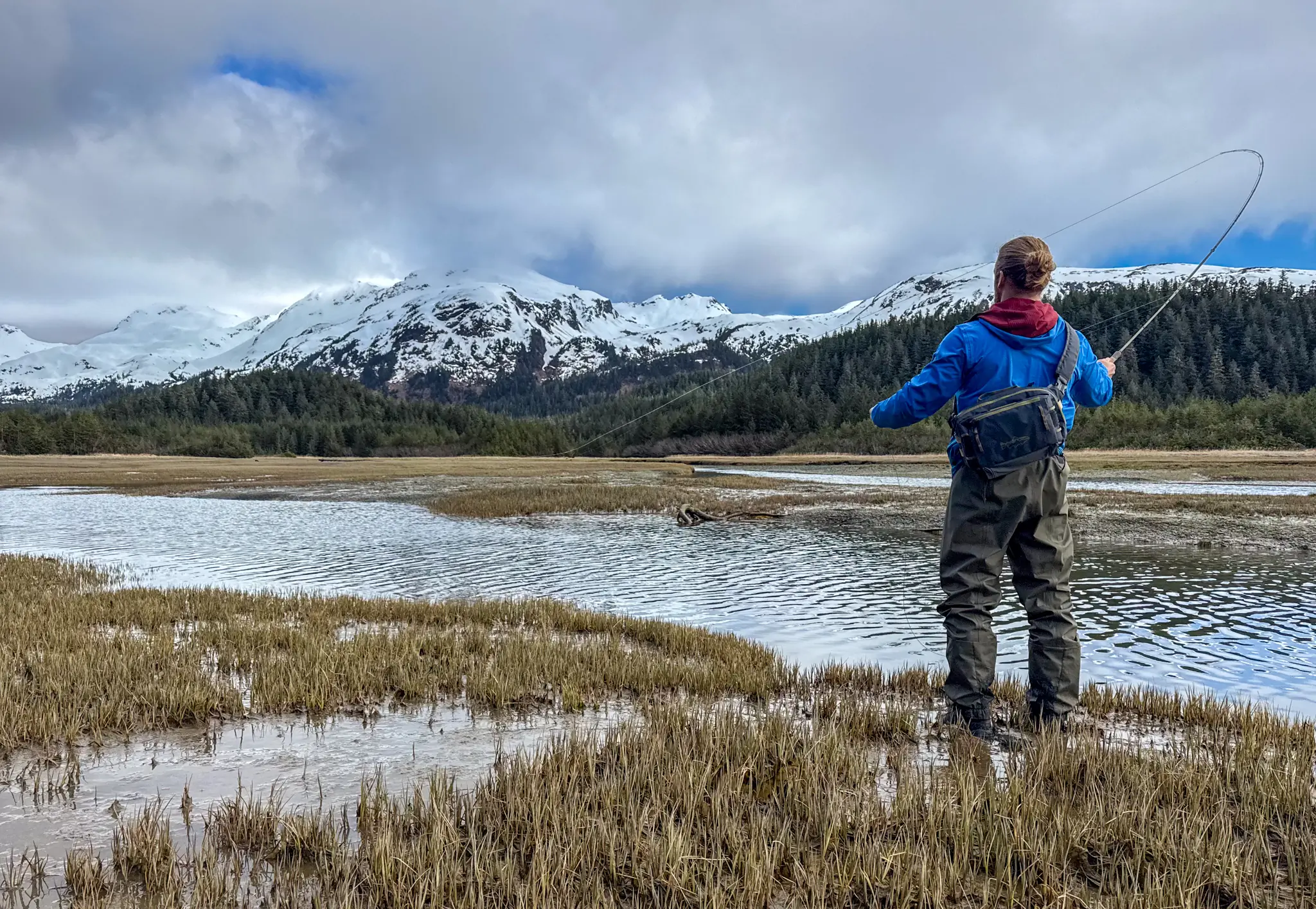Patagonia Swiftcurrent Traverse Waders worn by a person casting in front of snowy mountains
