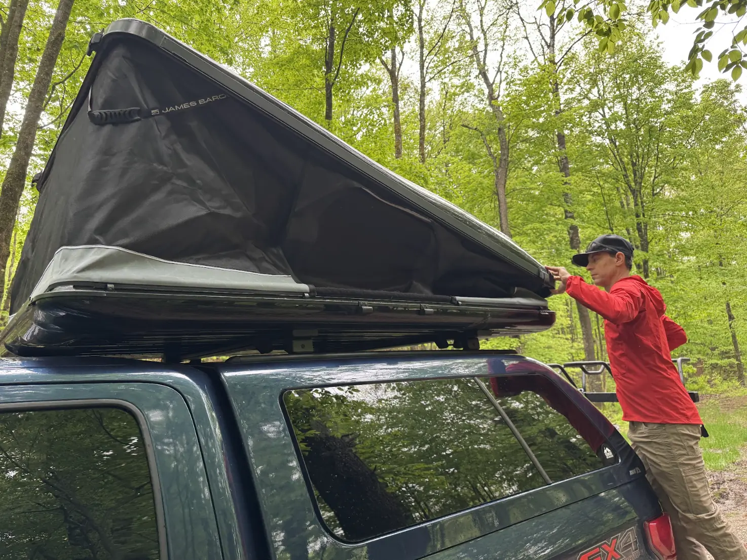Man setting up a James Baroud Odyssey mounted on a Ford F-150 in a forest