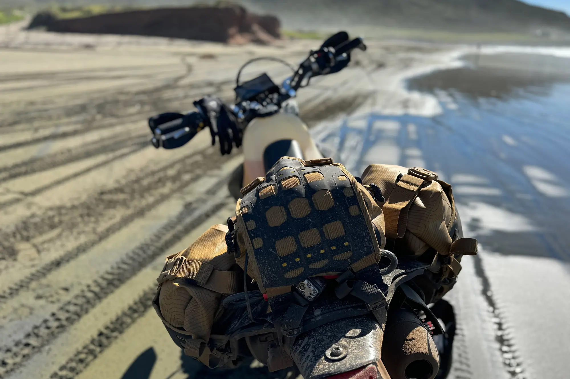 Mosko Moto Reckless 40L System V4.0 packed tightly on a dirt bike riding along the beach