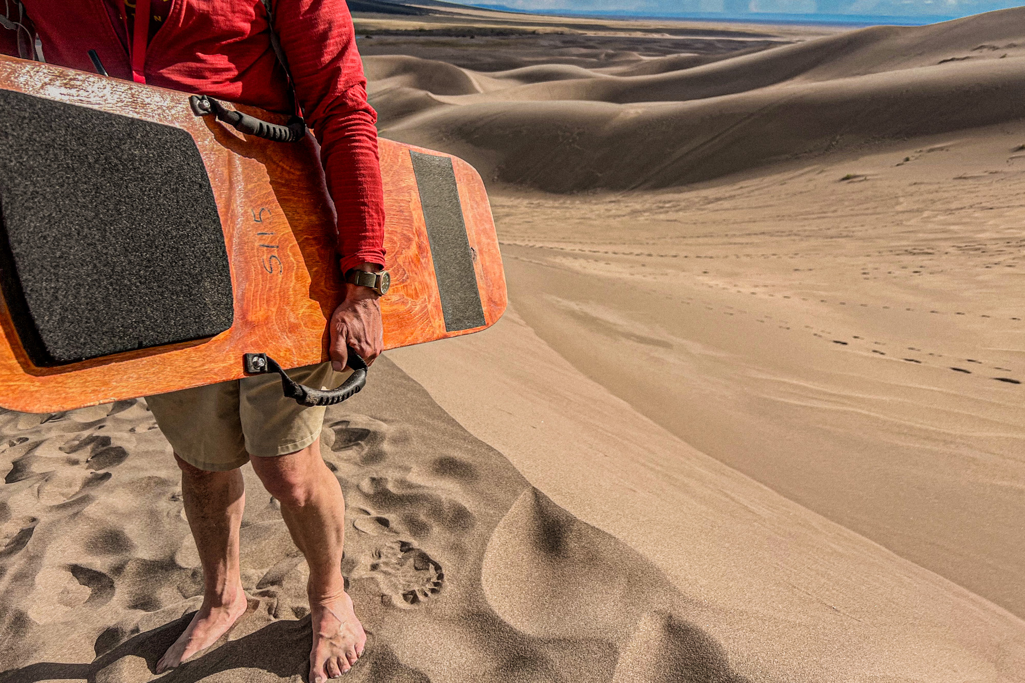 Man holding sand board wearing TUUL Filthy 13 watch on dune