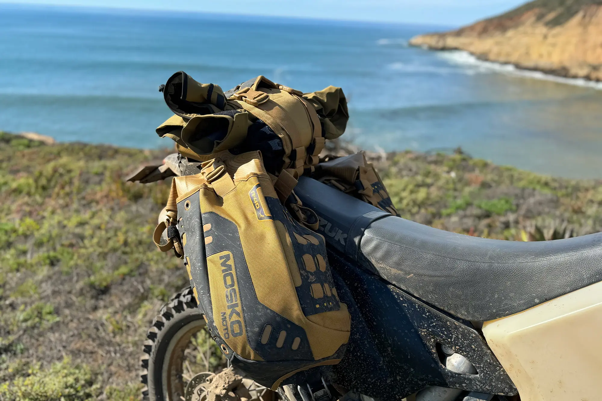 Mosko Moto Reckless 40L System V4.0 strapped securely on a dusty bike overlooking the ocean