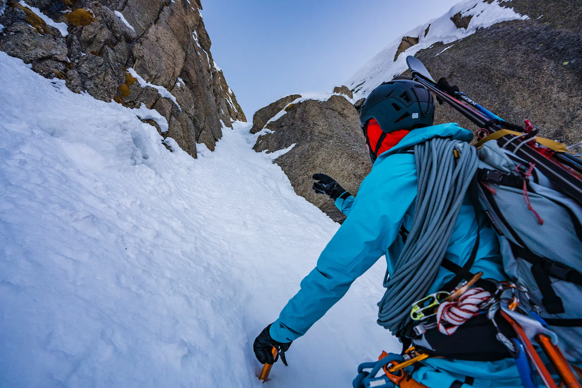 Vivian points toward a narrow snowy couloir between rocky walls
