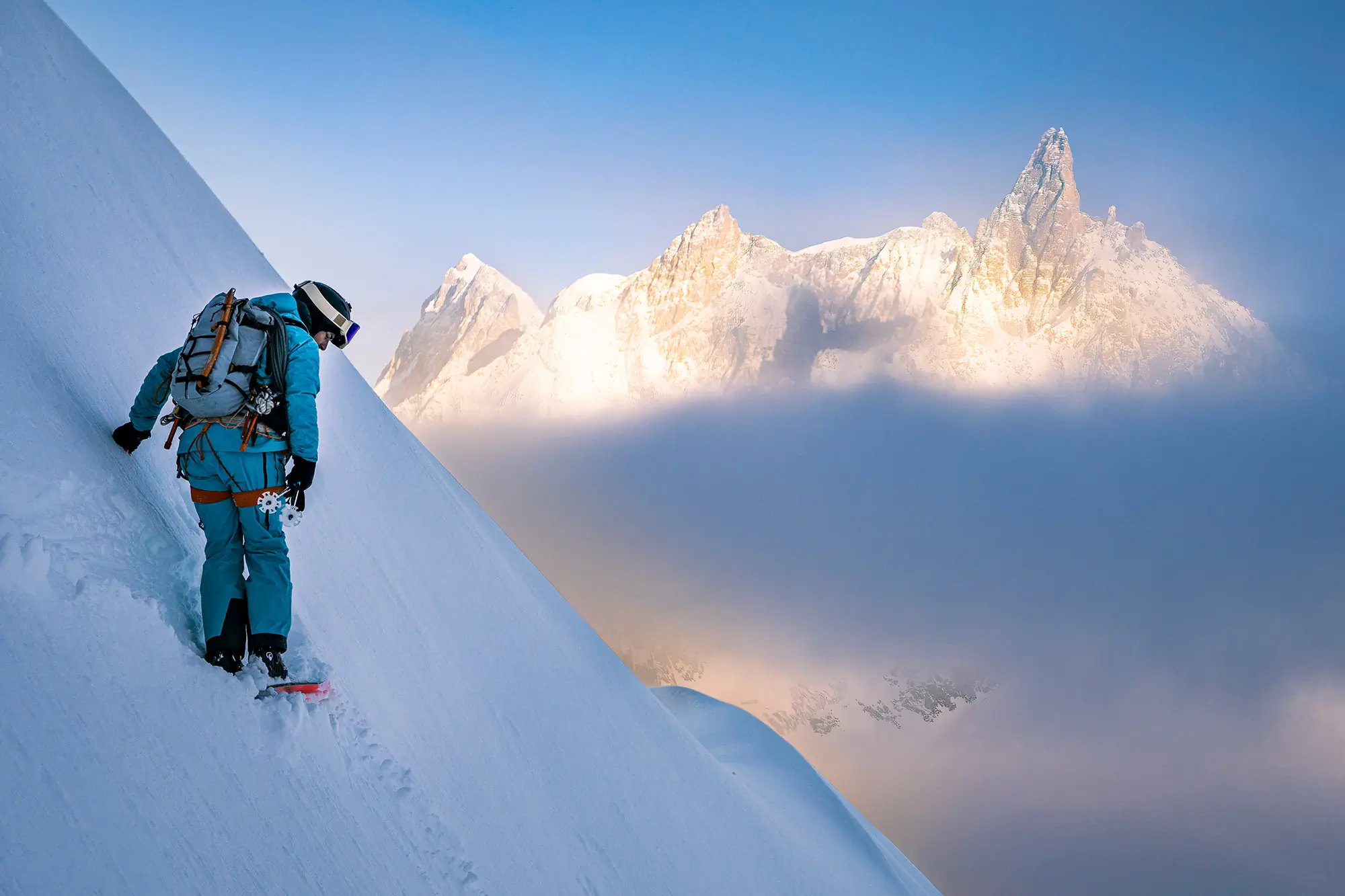 Vivian climbs above the clouds with peaks glowing in the sunrise
