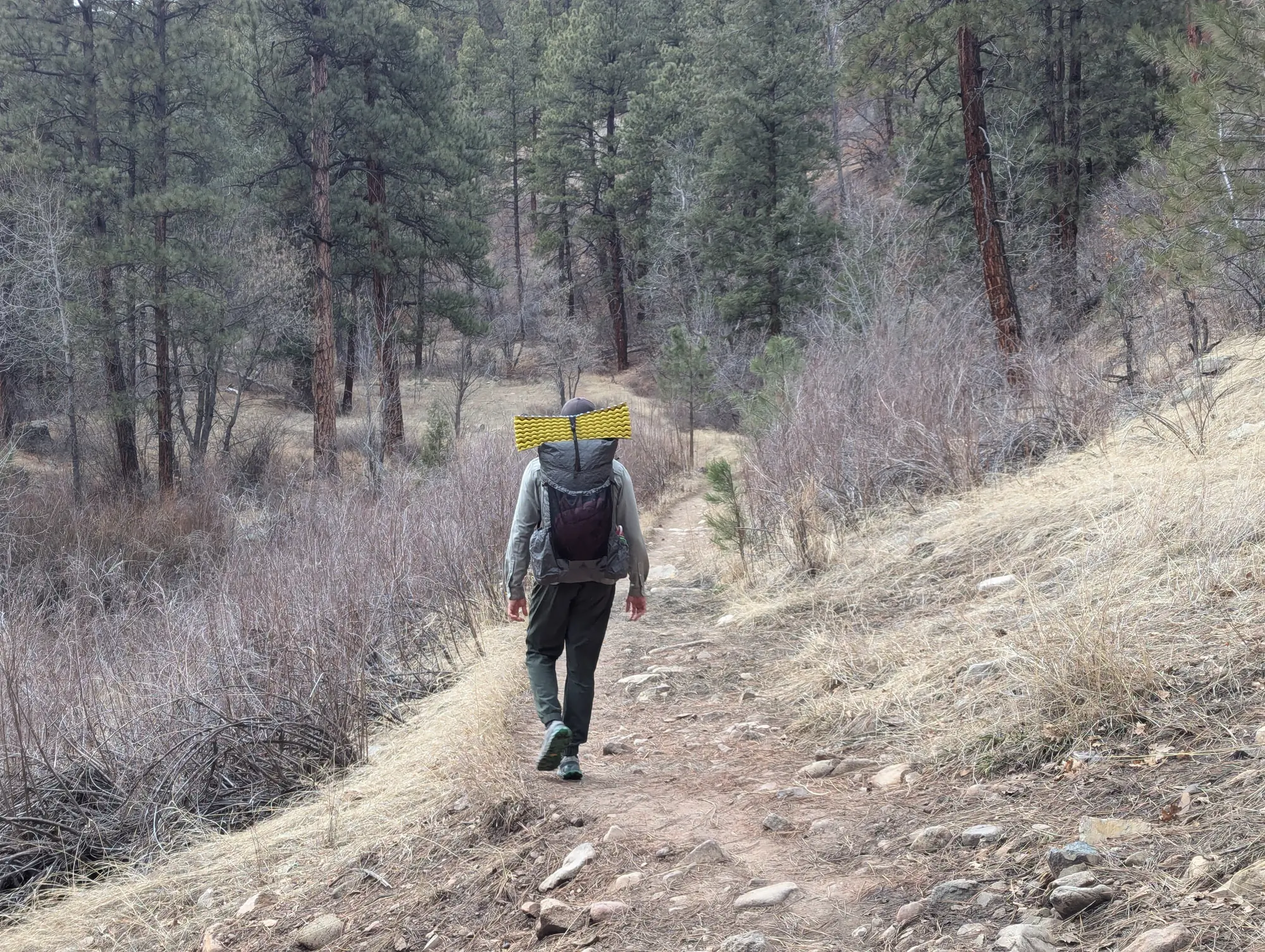a hiker hikes down a trail in colorado wearing the durston kakwa 55 pack