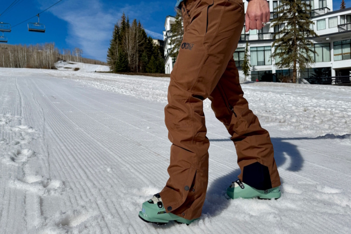 Person standing in snow wearing EXA snow pants with ski boots