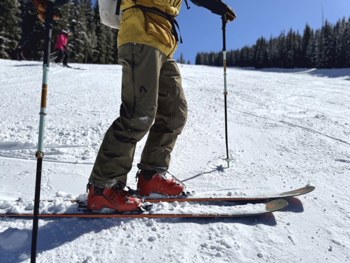 Person on skis in snow, wearing Flylow pants and holding trekking poles.