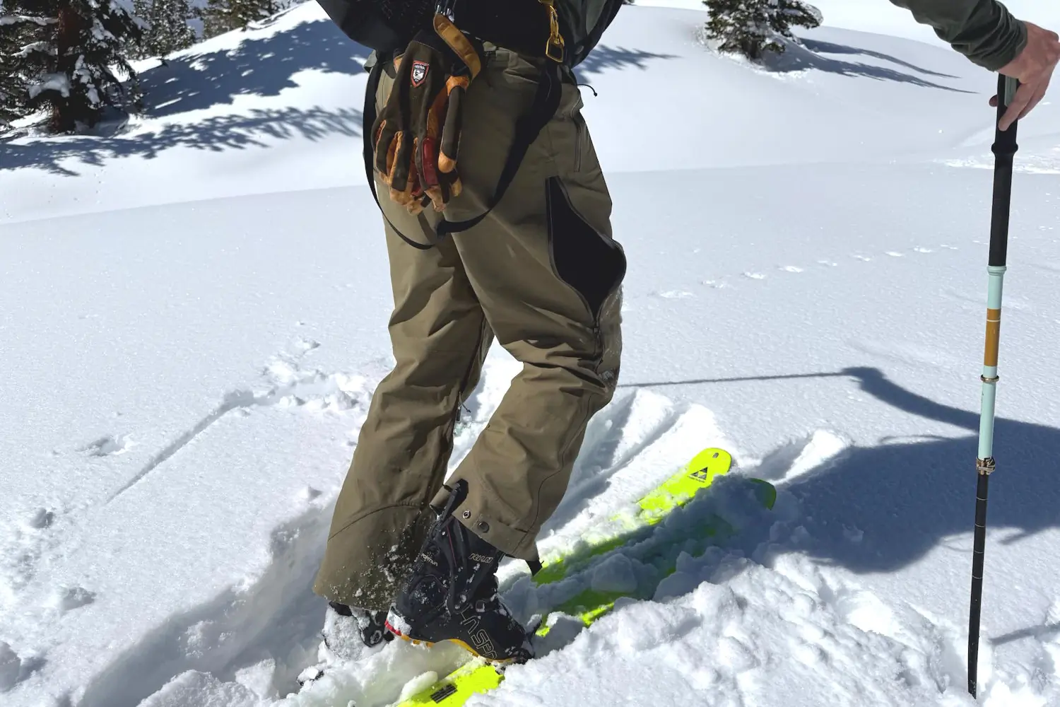Person in Flylow Chemical Pants on skis, holding a trekking pole in snowy terrain.