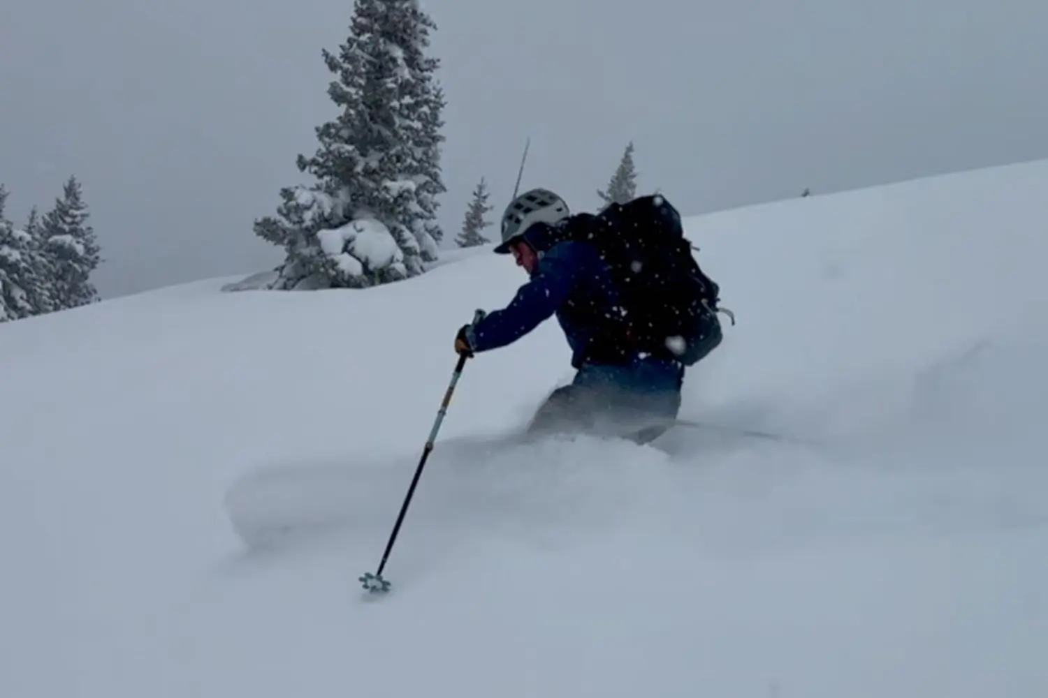 Man skiing through deep powder snow on a snowy mountain slope