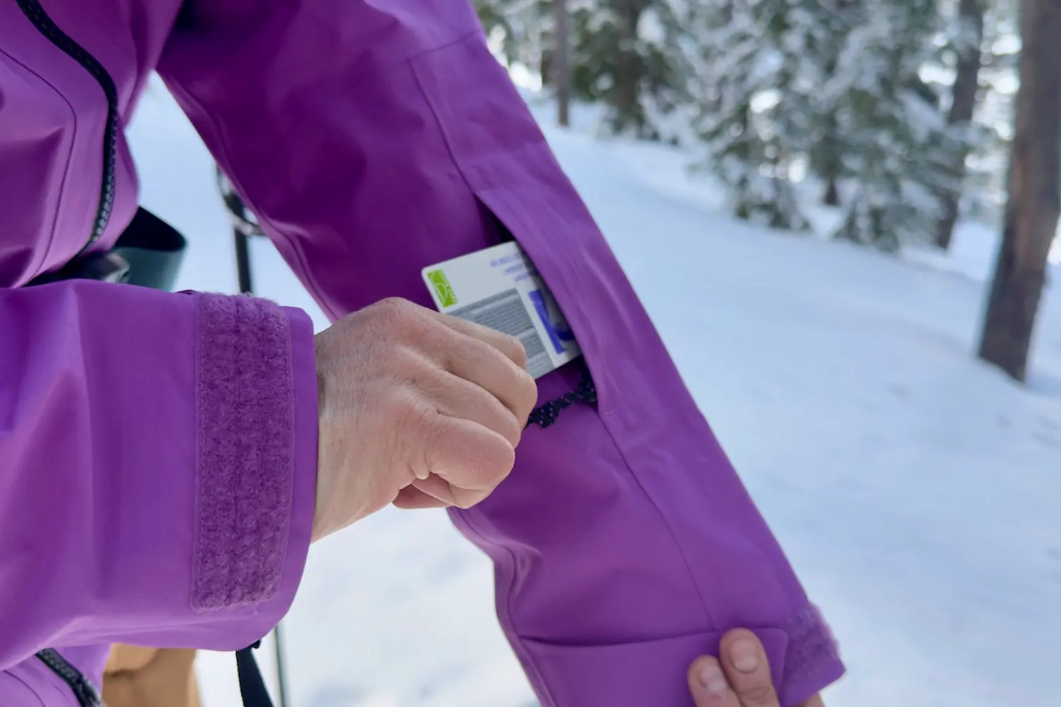 Close-up of the Mountain Hardwear Boundary Ridge Jacket sleeve pocket with a hand placing a card inside.