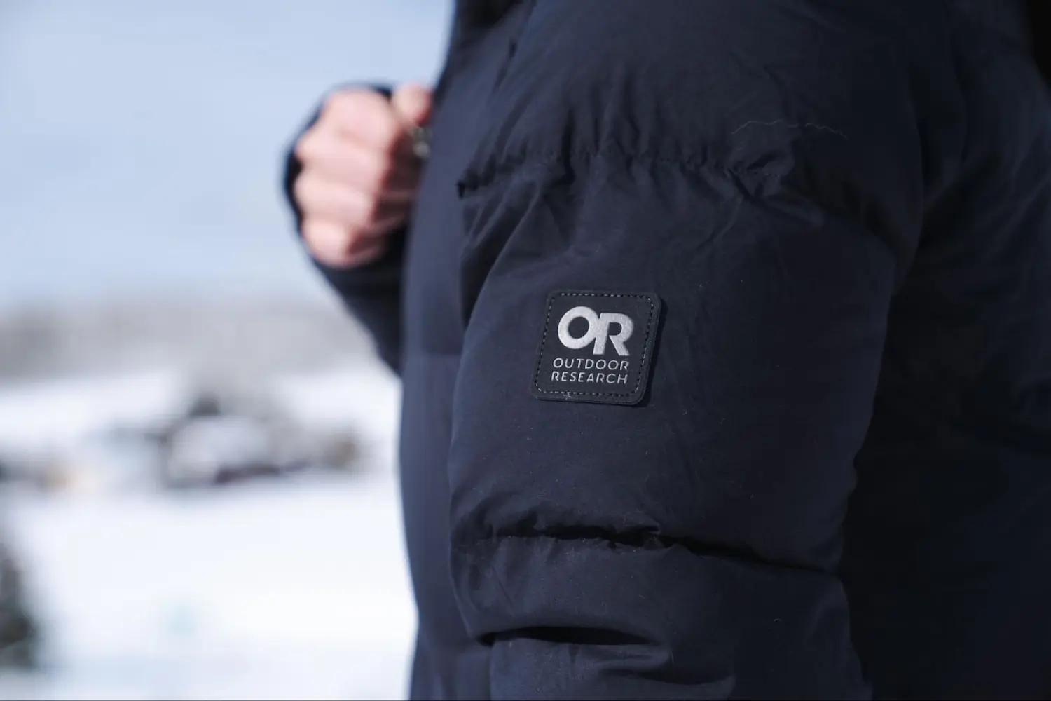 lose-up of the Outdoor Research Coze Down Parka sleeve showing the OR logo patch.