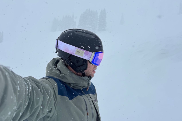 Person wearing a black ski helmet and Smith ski goggles in snow