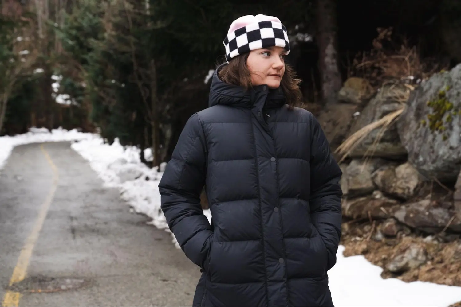 A woman stands outdoors in a winter setting wearing a black REI Co-op Norseland Down Parka