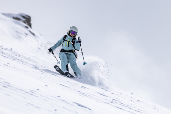 Skier tests the Columbia Platinum Peak II 3L Shell Jacket while carving through deep powder on a snowy mountain.