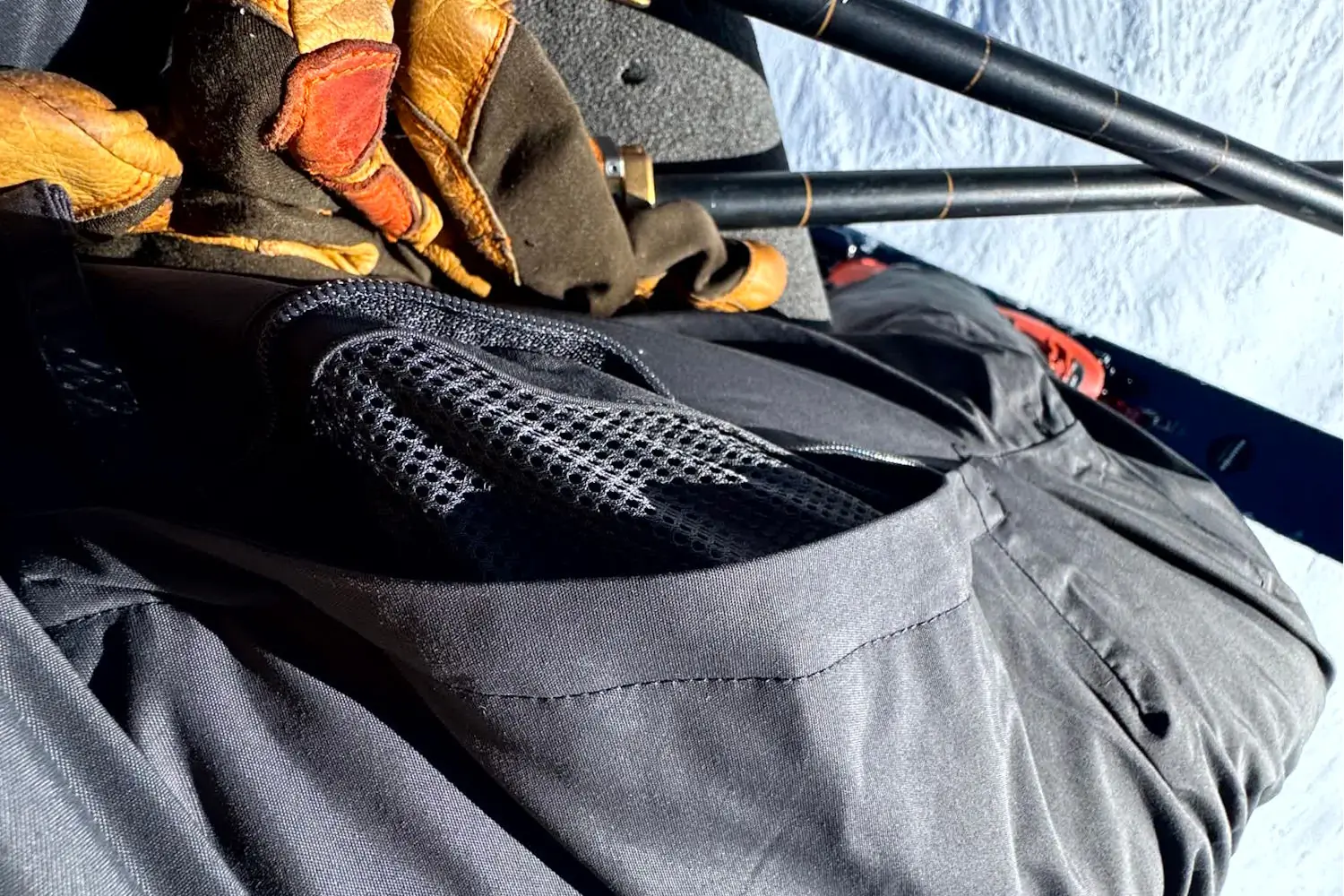 View of a skier sitting on a chairlift, showing The North Face Freedom Pants with inner thigh vents partially open and mesh backing visible.