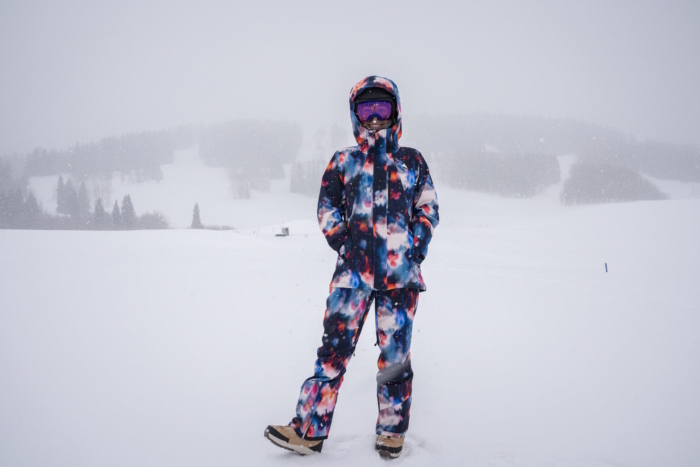 Women wearing a colorful Burton snow jacket stands in snow