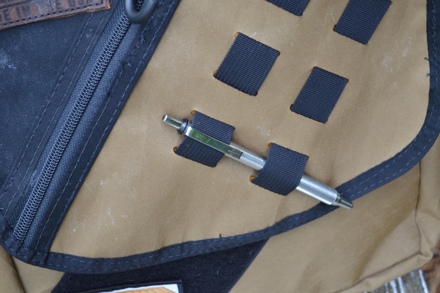 A steel pen is slipped into the MOLLE loop.