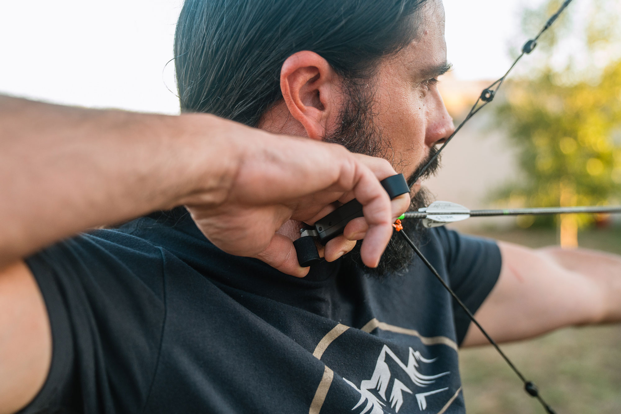 A man drawing a bow with an Evolution Outdoors Shadow Thumb Button Release