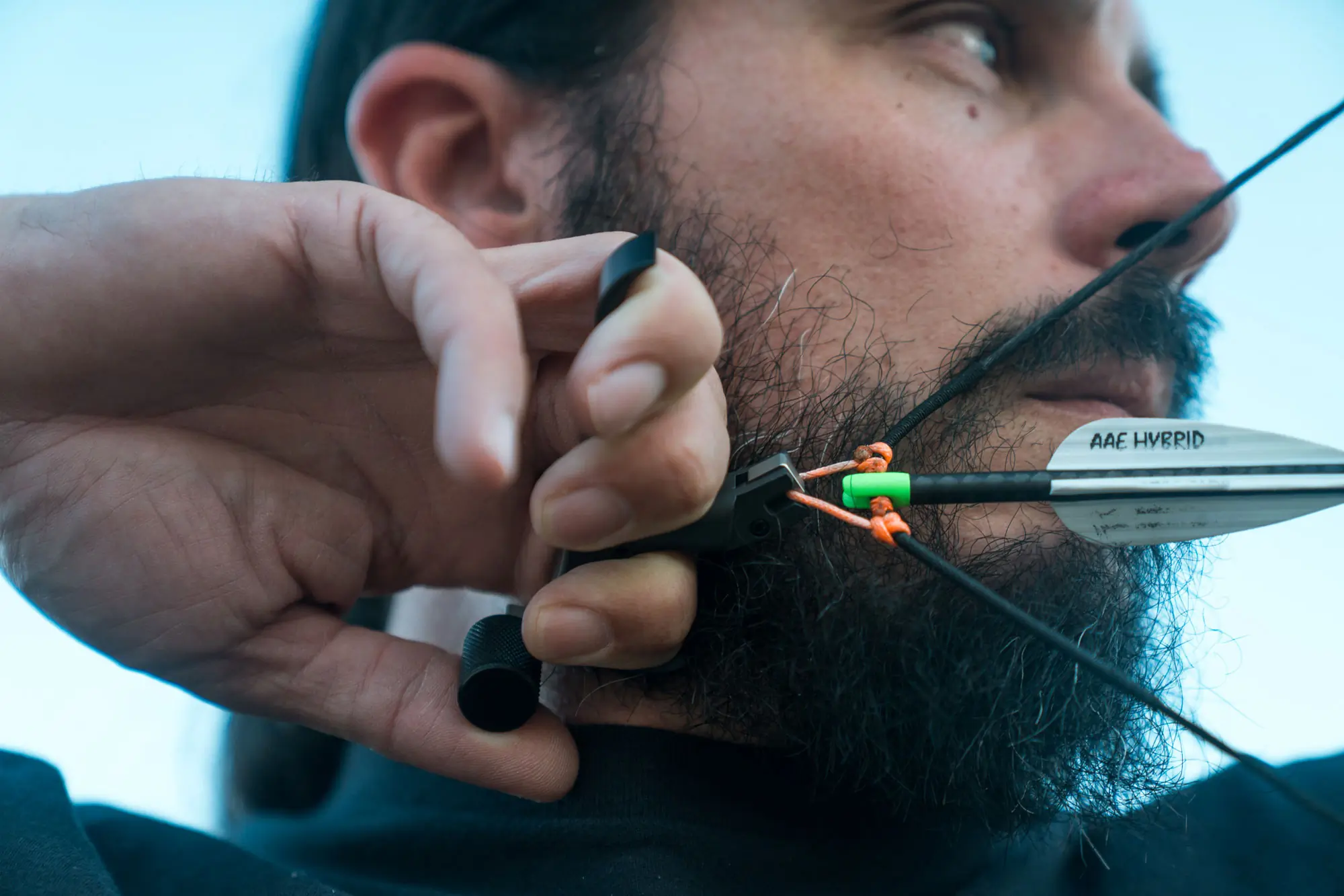 Close-up of a man drawing a bow with the Evolution Outdoors Shadow Thumb Button Release