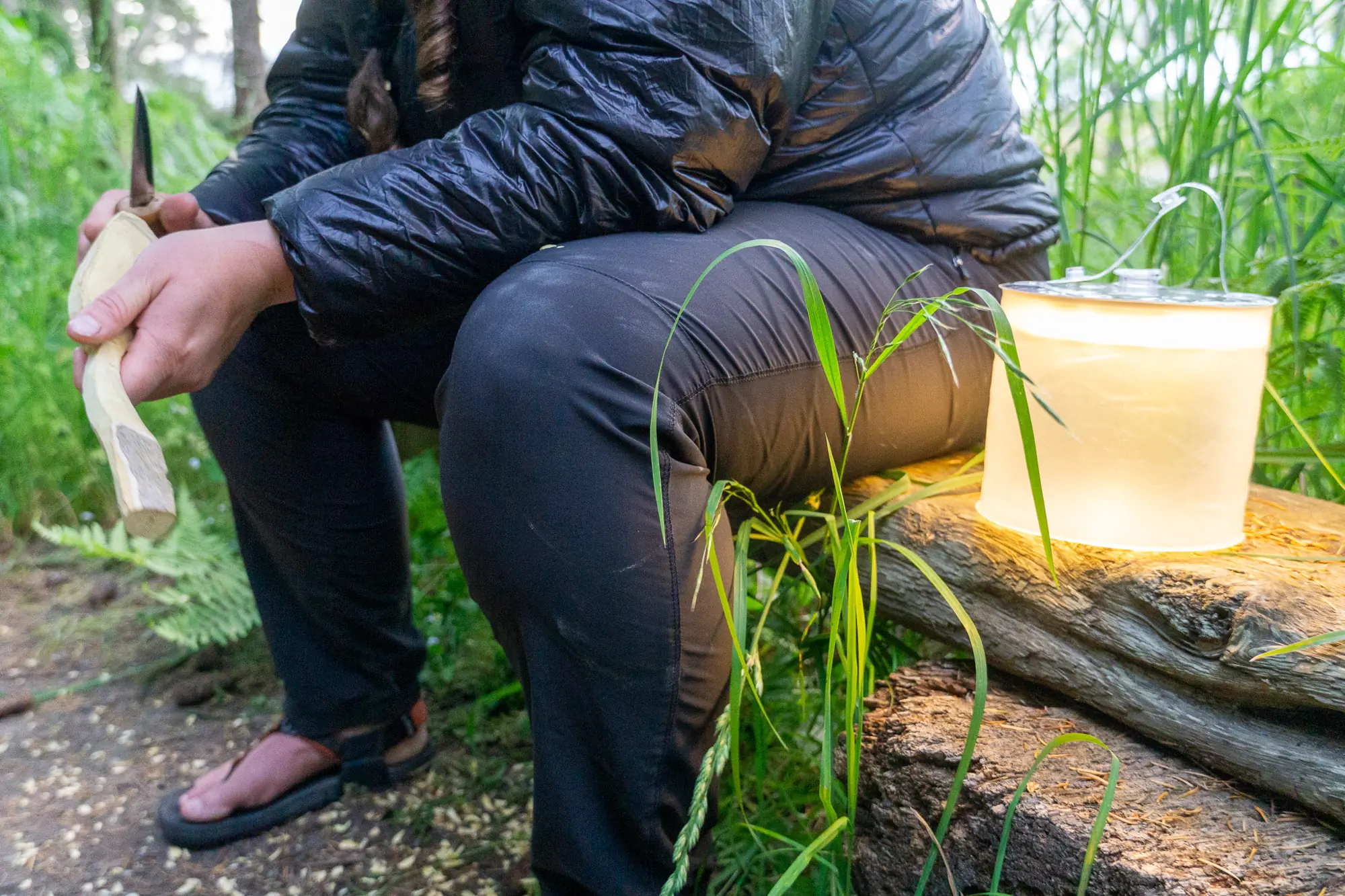the biolite luci charge 360 set beside a camper as she whittles a spoon