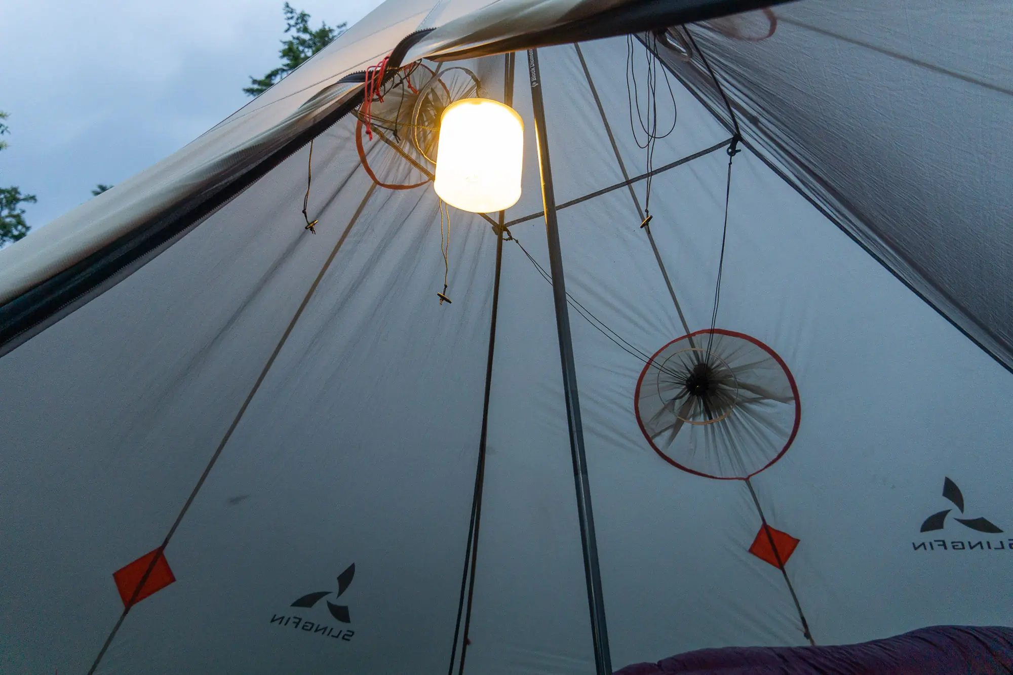 the biolite luci charge 360 hanging from the peak of a tarp shelter