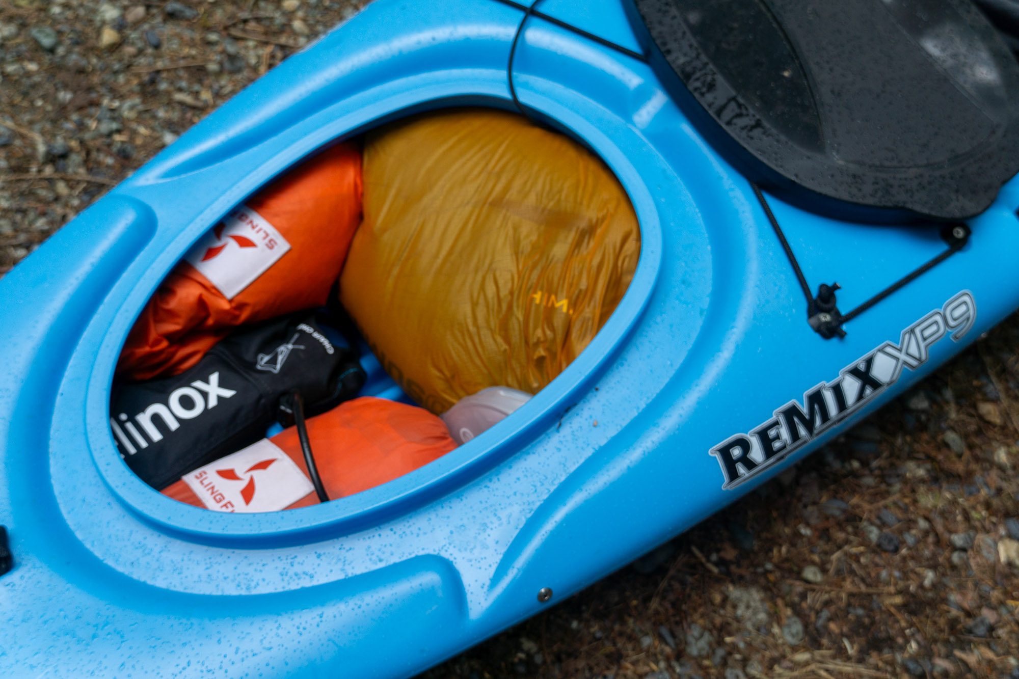 the stern hatch of the remix xp kayak open, showing camping kit stashed inside
